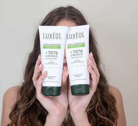 Model holding Luxéol shampoo and conditioner.