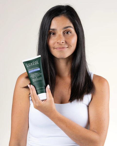 Woman holding a Luxeol product against a plain background