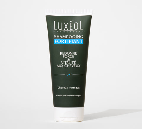 Tube of dark green Luxéol strenghtening shampoo on white background