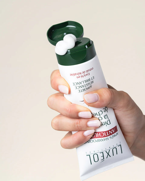 Hand holding a Luxsol product with a beige background