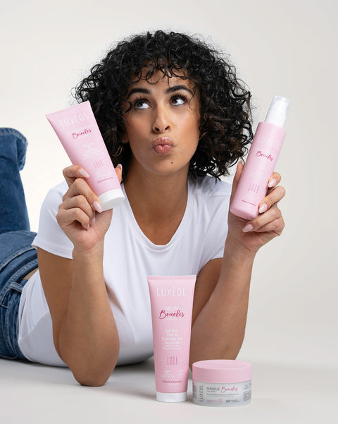 Женщина, держащая розовые средства по уходу за волосами на нейтральном фоне