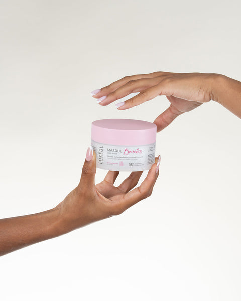 Две руки держат розовую и белую банку на нейтральном фоне