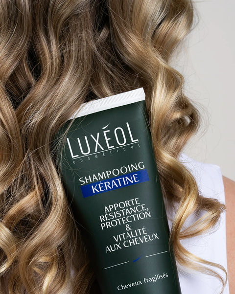 Luxéol keratin shampoo bottle with wavy hair in the background
