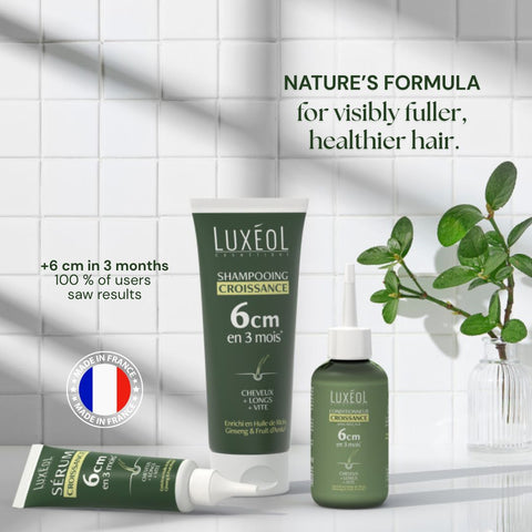 Luxéol matu kopšanas produkti ar tekstu uz flīžu sienas fona